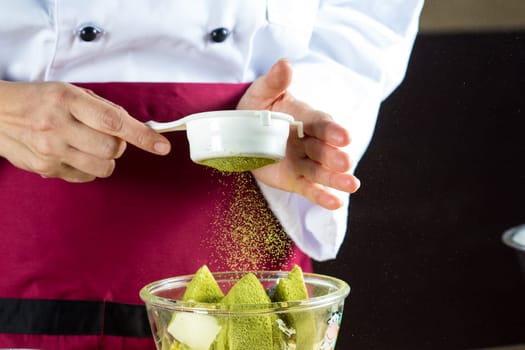 Chef sifting flour into pastry molds for making green tea cake