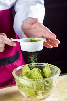 Chef sifting flour into pastry molds for making green tea cake