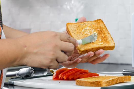 women hand spreading butter on toast