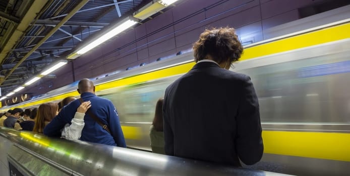 Passengers traveling by Tokyo metro. Business people commuting to work by public transport in rush hour. Shallow depth of field photo.