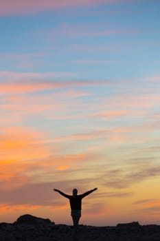 Silhouette of free woman enjoying freedom feeling happy at sunset. Serene relaxing woman in pure happiness and elated enjoyment with arms raised outstretched up.