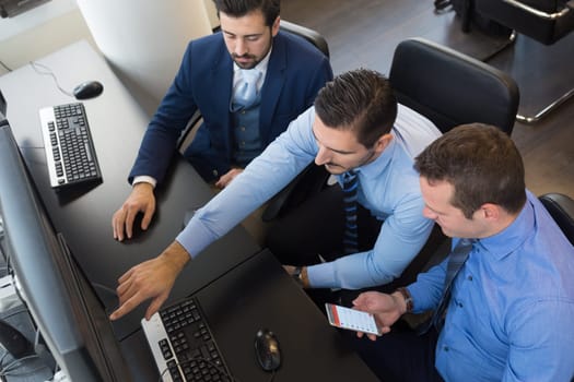 Businessmen trading stocks. Stock traders looking at graphs, indexes and numbers on multiple computer screens. Colleagues in discussion in traders office. Business success concept.
