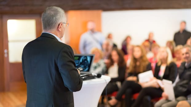 Speaker at Business Conference with Public Presentations. Audience at the conference hall. Entrepreneurship club. Rear view. Horisontal composition. Background blur.