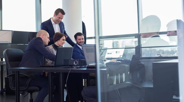 Workplace in modern office with business people brainstorming. Businessman working on laptop during the meeting.