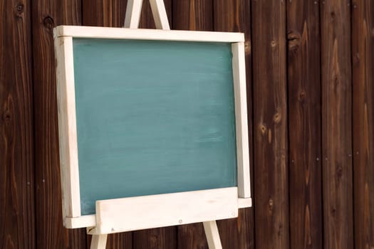 easel with blank chalkboard on a wood wall background