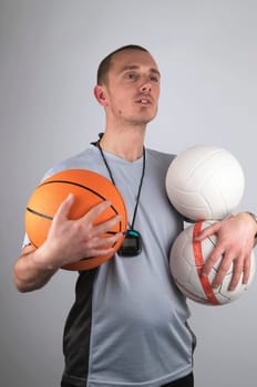 Coach is watching after his boys, holding a lot of balls.