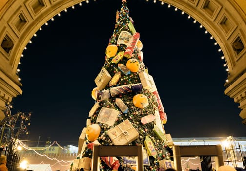Moscow, Russia - January 05, 2016: Big Christmas tree with ornaments on Red Square on night sky background near the entrance arch in GUM