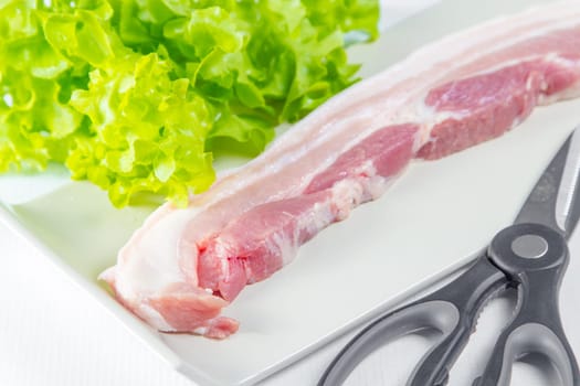 streaky pork with scissors in plate on white background