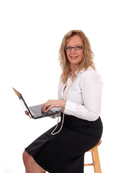 A business woman sitting in a black skirt white blouse holding.her laptop and working at it, isolated for white background..