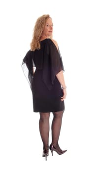 A serious looking woman standing isolated for white background from the.back in a black dress, looking over her shoulder..