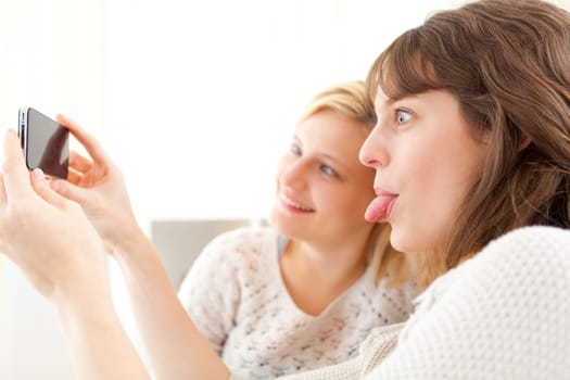 View of Girls on sofa taking selfie picture with smartphone