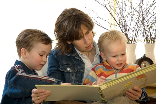 A young mother reading a book for her two son's.