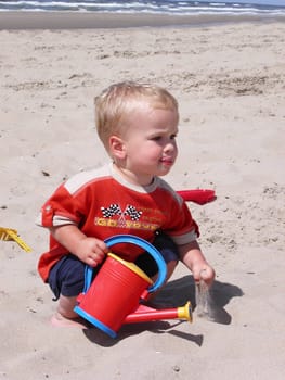 Little boy playing with sand on the beach