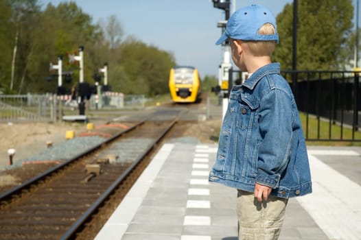 Little boy waiting for the train to come on a railway station.