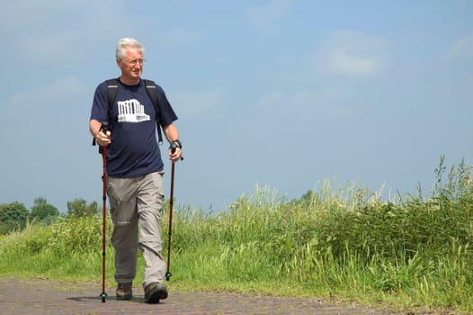 Senior man doing a Nordic Walk on a sunny day.