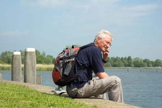 Senior man making a phone call home during his weekend trip at the harbour