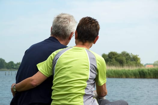 Senior couple sitting on a lonely place at a lake to think about their future and retirement.