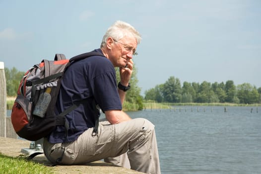 Senior man making a phone call home during his weekend trip at the harbour