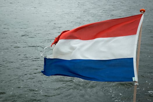 Dutch flag on a ship, against a wavy sea.