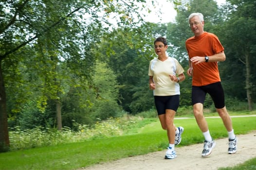 Senior couple running through the woods. Some motion blur.