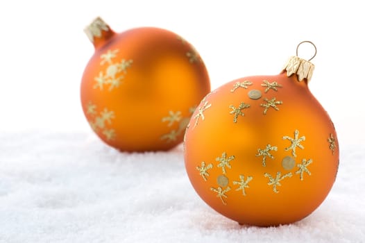 Two golden Christmas balls on snow. Isolated on white.