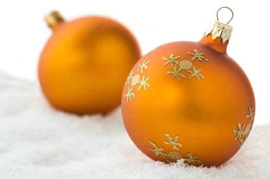 Two golden Christmas balls on snow. Isolated on white.