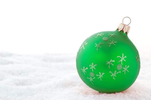 Green Christmas ball on snow. Isolated on white.
