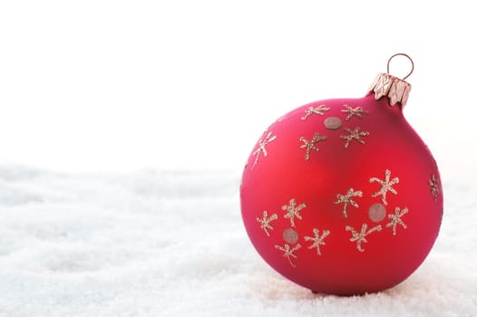 Red Christmas ball on snow. Isolated on white.