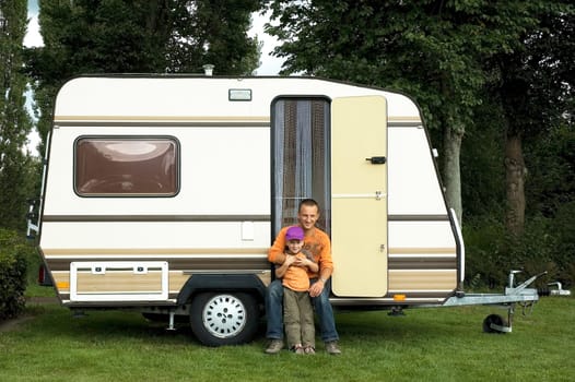 Father and son sitting in front of a caravan