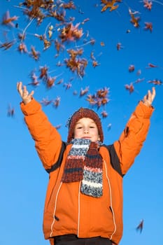 This boy is happy that the autumn has started! He likes to throw with the beautiful colored leaves. Movement in the leaves.
