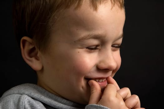 7 year old boy having fun. Against a black background.