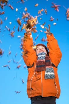 This boy is happy that the autumn has started! He likes to throw with the beautiful colored leaves. Movement in the leaves.