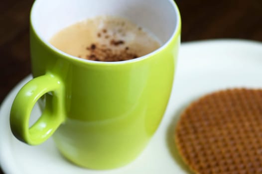 A delicious cup of cappuchino with a cookie.