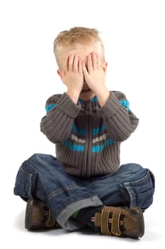 Boy holding his hands against his eyes.