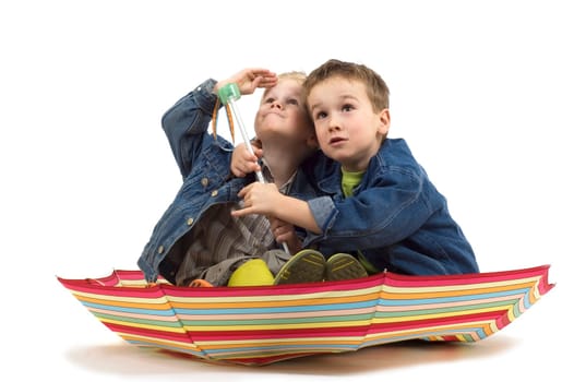 Two boys sitting in an umbrella, like it's a boat. They're watching if the storm is coming.