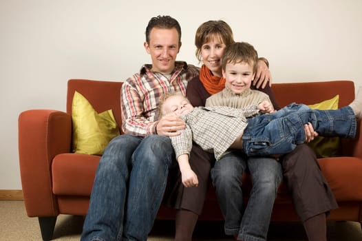 Nice family picture, sitting together on a couch.