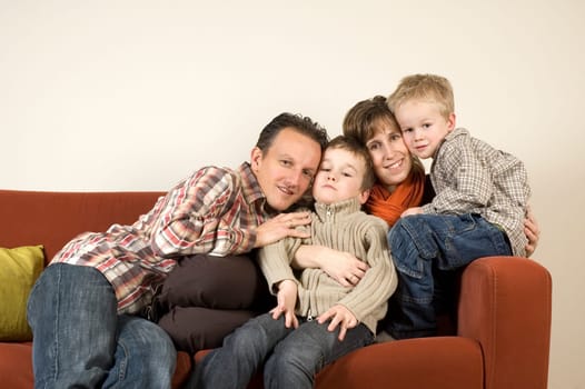 Nice family picture, sitting together on a couch.