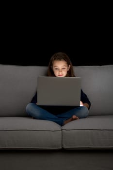 Little girl sitting on a desk and working with a computer