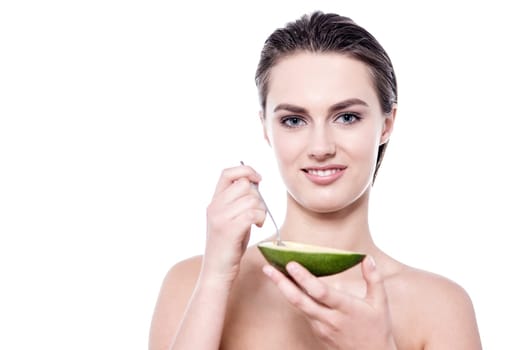 Pretty young woman showing avocado to camera