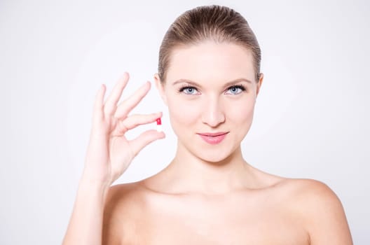 Naked woman holding a pill