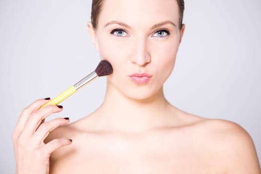 Bare shoulders attractive lady  applying blusher