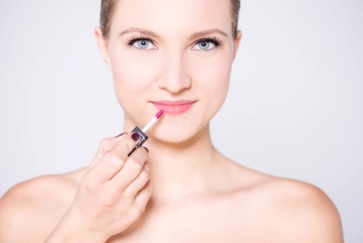 Graceful model putting on sparkling lipstick