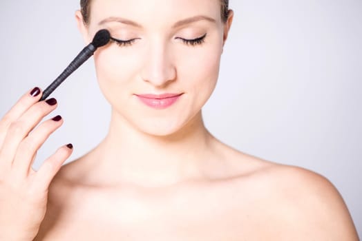 Charismatic woman using eye shadow brush
