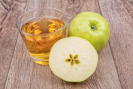 Green apples and juice on a wooden background