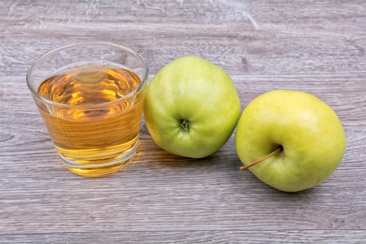 Green apples and juice on a wooden background