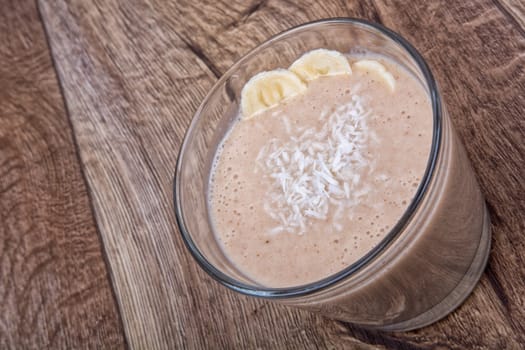 Chocolate drink with coconut and banana on a wooden background