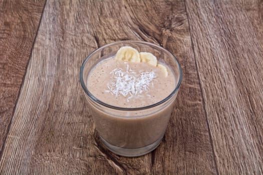 Chocolate drink with coconut and banana on a wooden background