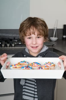 Boy is showing his just baked cupcakes