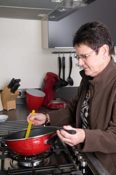 Senior woman in a modern kitchen cooking a meal.