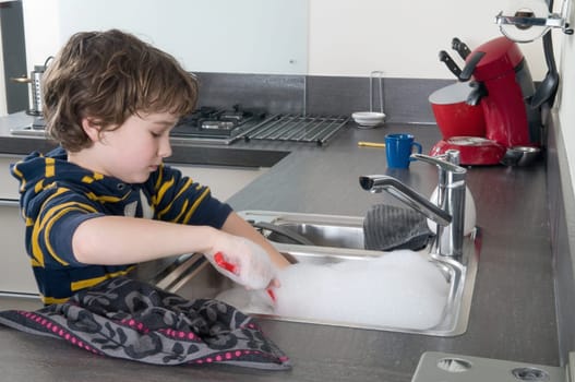 Boy doing the dishes in a modern kitchen